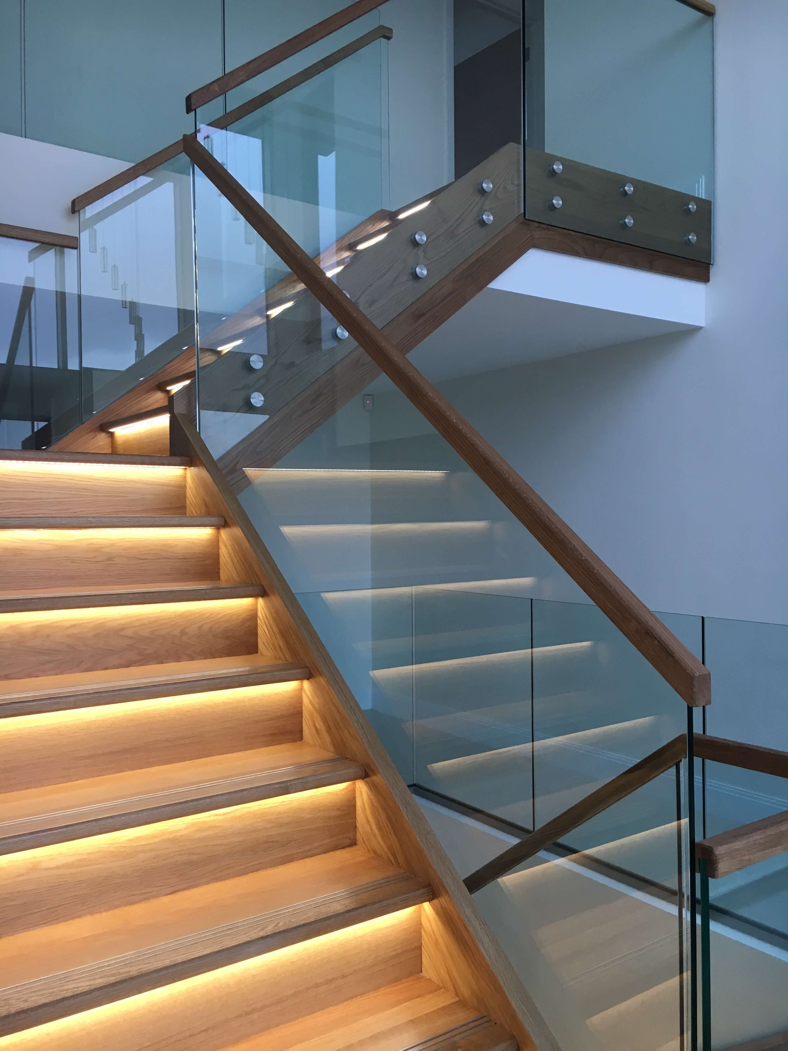Modern staircase with glass balusters and lights